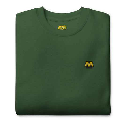 Groene trui met het Metro logo geborduurd op de borst, ontwerp door De Zwarte Markt en verkrijgbaar bij cadeauwinkel 'A Given Horse'. Gevouwen.